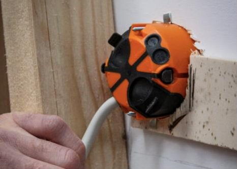 Orangefarbene winddichte Elektro-Dose beim Einbau in eine Holzwand